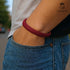 Rotes Lederarmband am Handgelenk eines Mannes – ein eleganter Glücksbringer für Stärke, Charakter und Leidenschaft. Vereint Stilbewusstsein mit lässiger Klasse. Uniqal